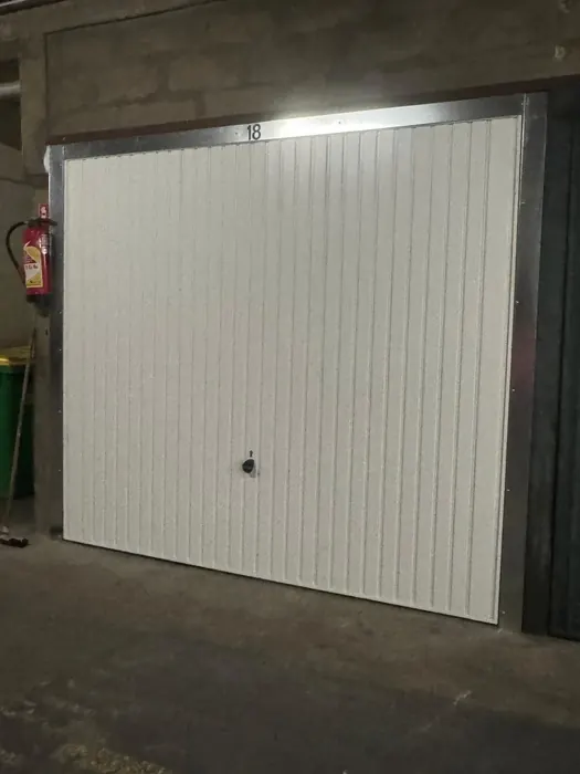Après : Porte métallique abîmée remplacée par une porte basculante blanche